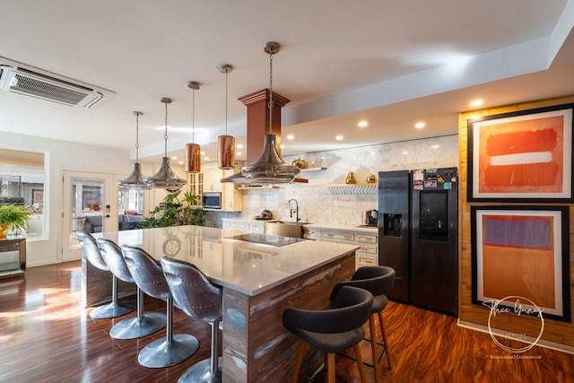 kitchen with visible vents, a breakfast bar, dark wood finished floors, black appliances, and a center island