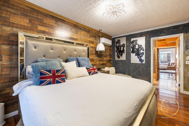 bedroom with wood finished floors, a textured ceiling, ornamental molding, and a wall mounted AC