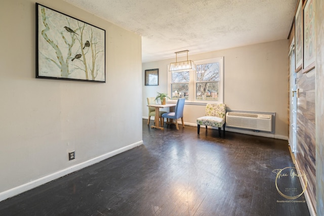 unfurnished room with dark wood finished floors, baseboards, a wall mounted air conditioner, and a textured ceiling