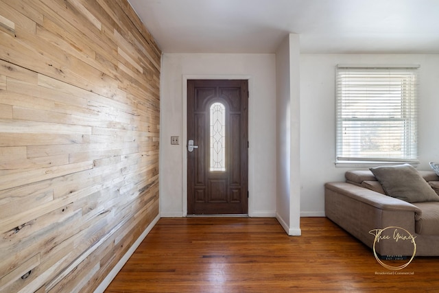 foyer featuring wood walls, baseboards, and wood finished floors