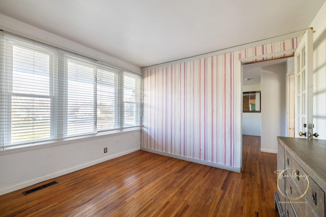 spare room with visible vents, baseboards, and dark wood finished floors