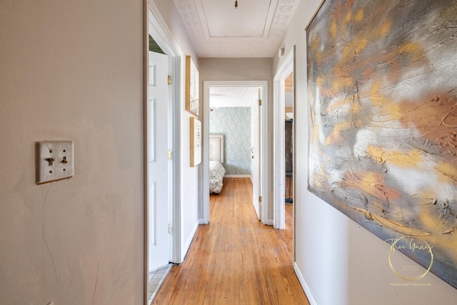 hallway with light wood-style flooring, wallpapered walls, and baseboards