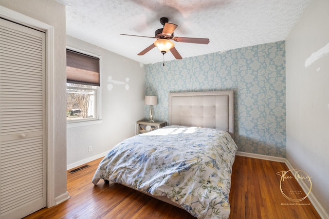 bedroom with visible vents, baseboards, a textured ceiling, and wallpapered walls