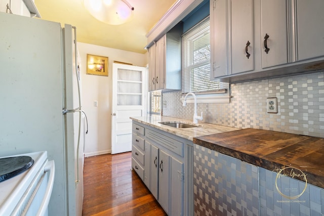 kitchen with a sink, white appliances, backsplash, and gray cabinetry