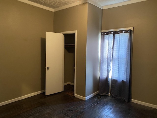 unfurnished bedroom featuring a closet, crown molding, dark hardwood / wood-style floors, and a textured ceiling