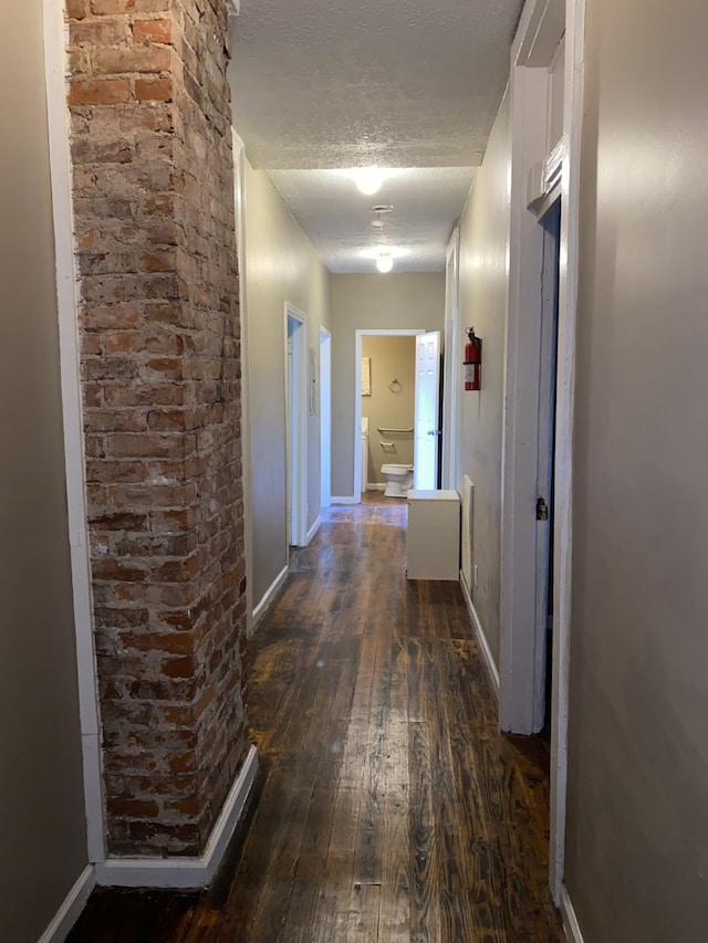 corridor featuring dark wood-type flooring and a textured ceiling