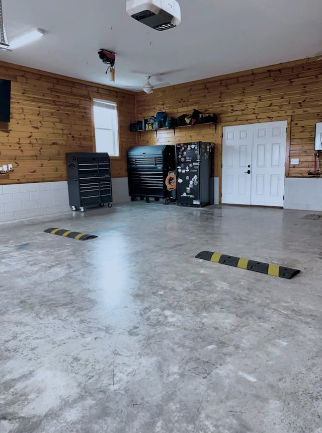 garage with a garage door opener and wood walls