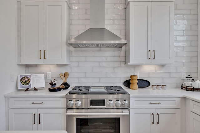 kitchen with tasteful backsplash, white cabinetry, wall chimney range hood, and stainless steel gas stove