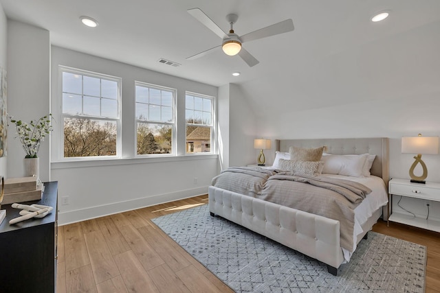 bedroom with ceiling fan, lofted ceiling, and light wood-type flooring