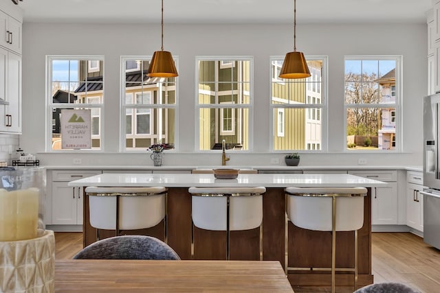 kitchen with a kitchen island, a breakfast bar, decorative backsplash, and white cabinets