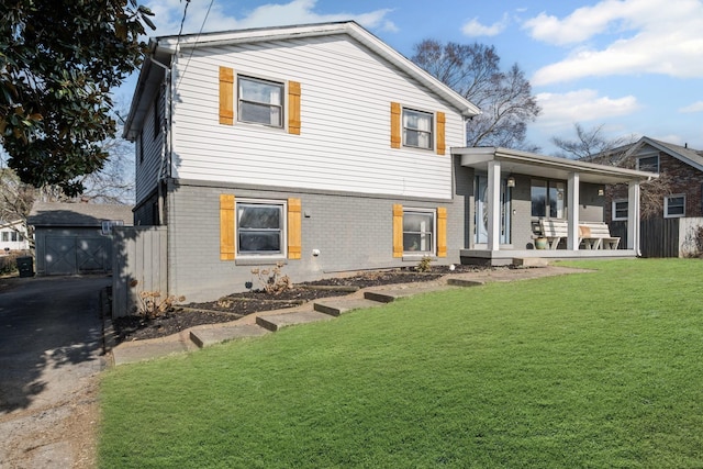 back of property with covered porch and a lawn