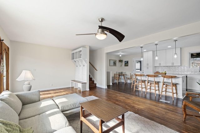 living room with dark wood-type flooring, ceiling fan, and a healthy amount of sunlight