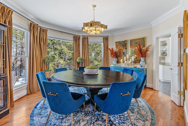 dining area with crown molding, light hardwood / wood-style floors, and a chandelier