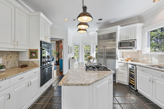 kitchen with white cabinets, appliances with stainless steel finishes, beverage cooler, and decorative light fixtures