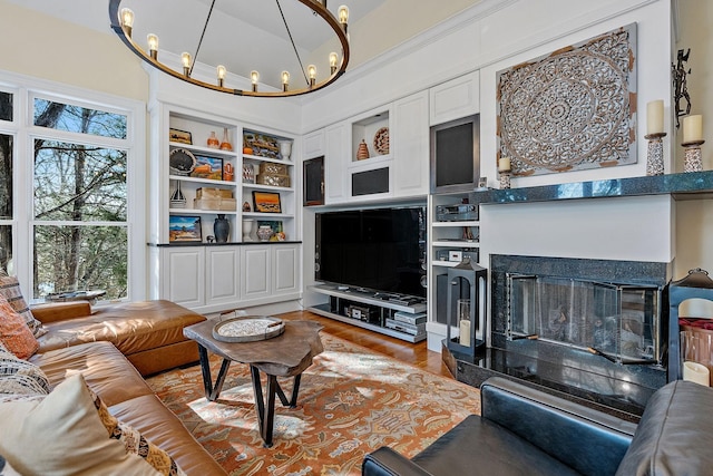 living room featuring a high ceiling, hardwood / wood-style floors, built in features, and an inviting chandelier