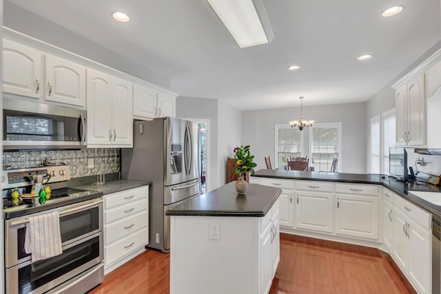 kitchen featuring white cabinetry, appliances with stainless steel finishes, decorative backsplash, and pendant lighting