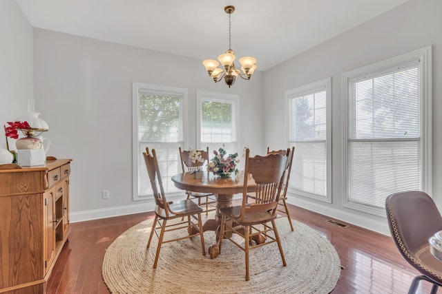 dining space with dark wood-type flooring and a chandelier