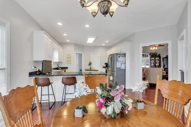 dining space with a healthy amount of sunlight, ceiling fan with notable chandelier, and wood-type flooring