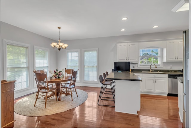 kitchen with sink, a breakfast bar area, decorative light fixtures, stainless steel dishwasher, and white cabinets