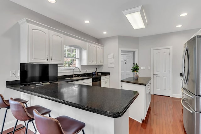 kitchen with a breakfast bar, white cabinetry, sink, kitchen peninsula, and stainless steel appliances