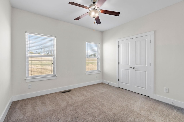 unfurnished bedroom featuring ceiling fan, light colored carpet, and a closet