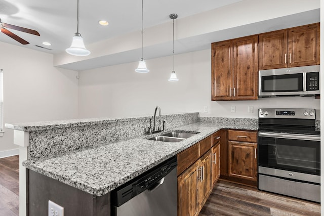 kitchen with sink, appliances with stainless steel finishes, hanging light fixtures, dark hardwood / wood-style flooring, and kitchen peninsula