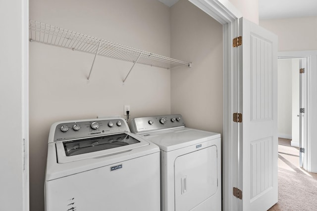 clothes washing area with light colored carpet and washing machine and clothes dryer