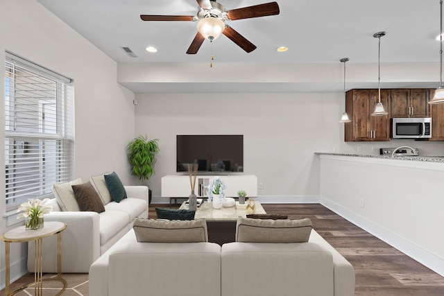 living room featuring dark wood-type flooring and ceiling fan