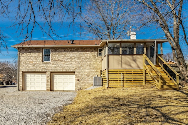 view of front of home featuring a garage, a sunroom, and central AC unit