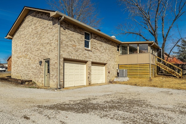 view of side of home featuring cooling unit, a garage, and a sunroom