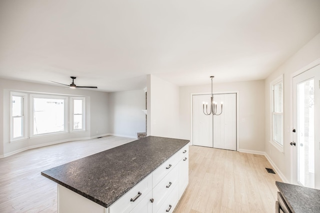 kitchen with a kitchen island, ceiling fan with notable chandelier, white cabinets, hanging light fixtures, and light wood-type flooring