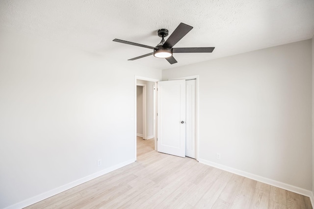 empty room with ceiling fan, light hardwood / wood-style floors, and a textured ceiling