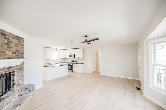 unfurnished living room with ceiling fan, a fireplace, and light hardwood / wood-style flooring