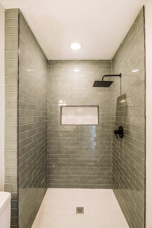 bathroom featuring toilet and tiled shower