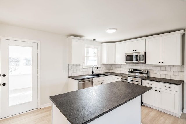 kitchen with white cabinetry, sink, decorative backsplash, hanging light fixtures, and stainless steel appliances