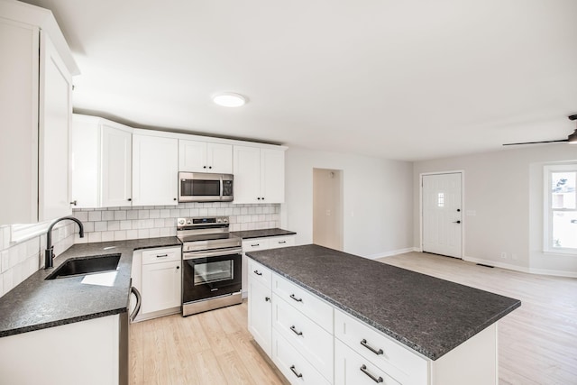 kitchen featuring sink, stainless steel appliances, a center island, and white cabinets