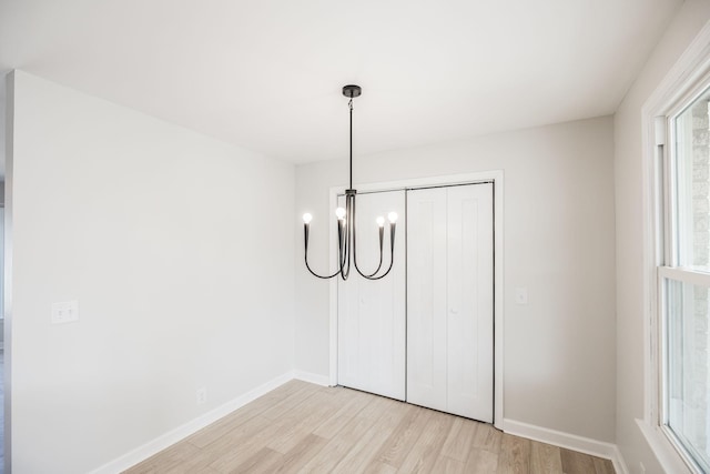 unfurnished bedroom featuring a closet, a chandelier, and light wood-type flooring