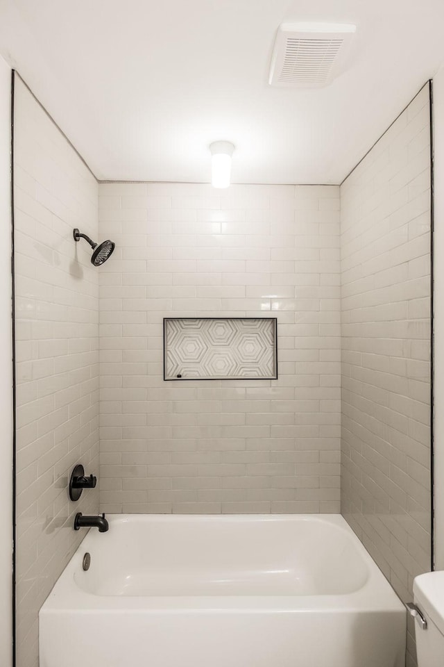 bathroom featuring tiled shower / bath combo and toilet