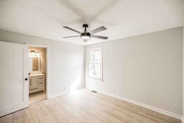 unfurnished bedroom with ceiling fan, connected bathroom, light hardwood / wood-style floors, and a textured ceiling