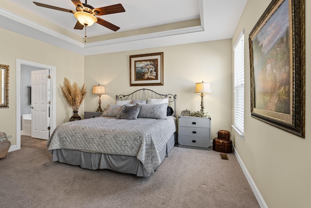 carpeted bedroom featuring ceiling fan, ensuite bathroom, and a tray ceiling