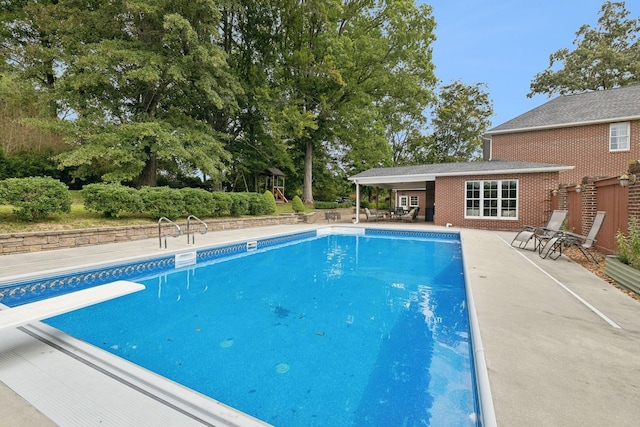 view of swimming pool featuring an outbuilding, a diving board, and a patio