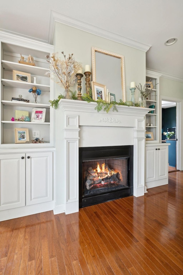 interior details with crown molding, wood-type flooring, and built in shelves