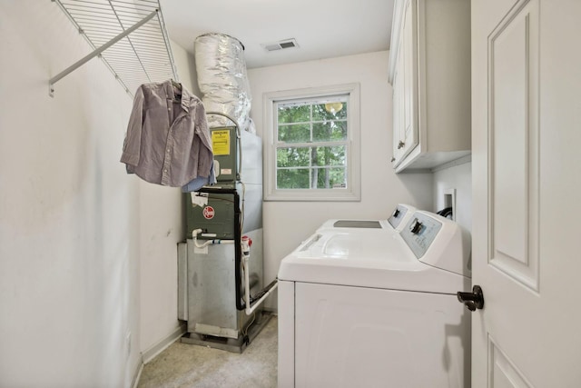 washroom featuring cabinets, heating unit, and washer and clothes dryer