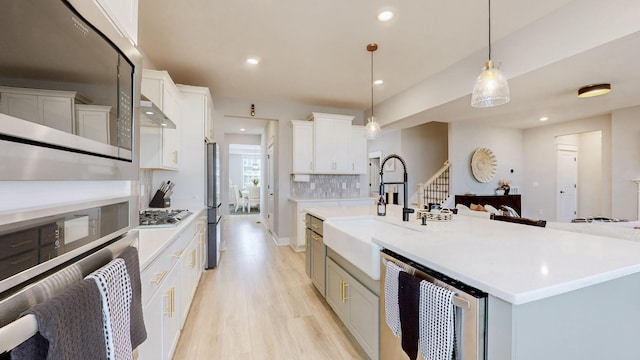 kitchen with a spacious island, sink, decorative light fixtures, stainless steel appliances, and white cabinets