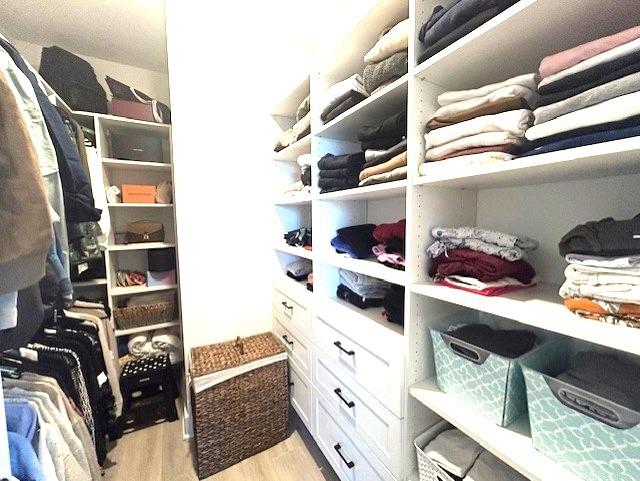 walk in closet with light hardwood / wood-style floors