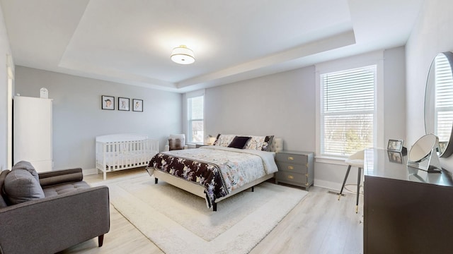 bedroom with a tray ceiling and light hardwood / wood-style floors