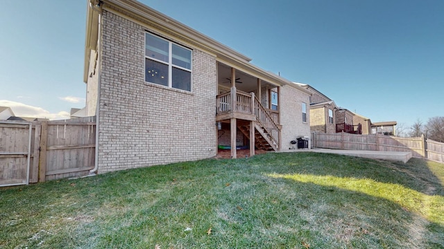 rear view of house with ceiling fan and a yard