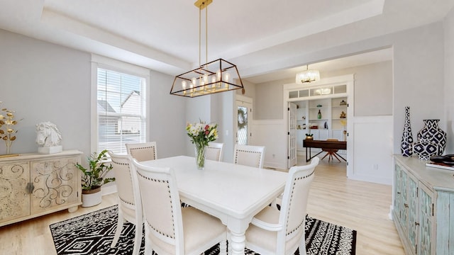 dining space featuring a tray ceiling and light hardwood / wood-style flooring