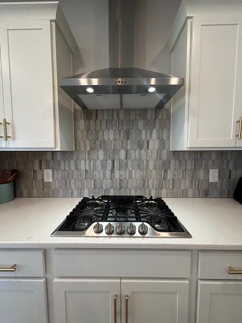 kitchen with island range hood, decorative backsplash, white cabinets, and stainless steel gas cooktop