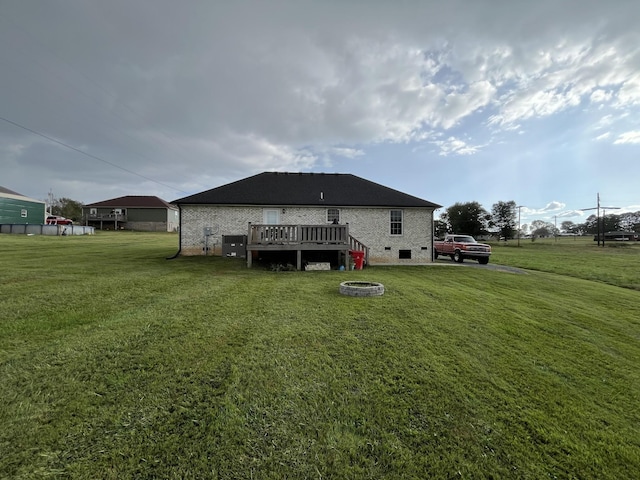 back of house featuring a wooden deck, a lawn, central AC unit, and a fire pit